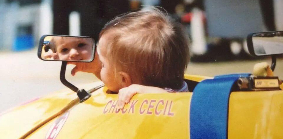 Baby looking in rearview mirror of yellow race car