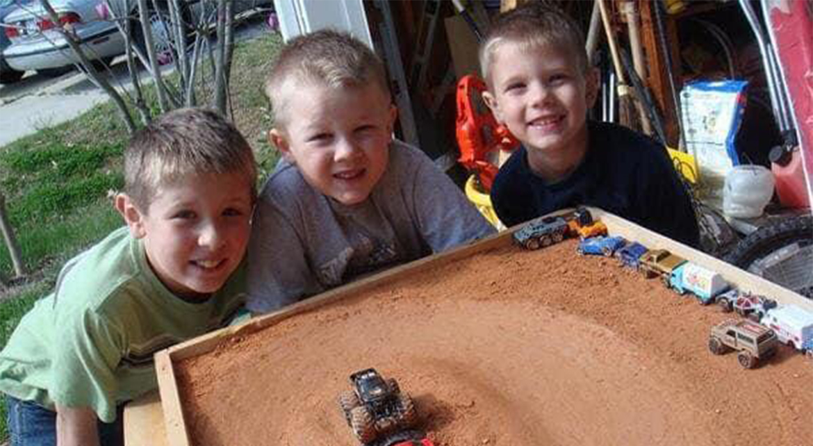 Three boys playing with matchbox cars