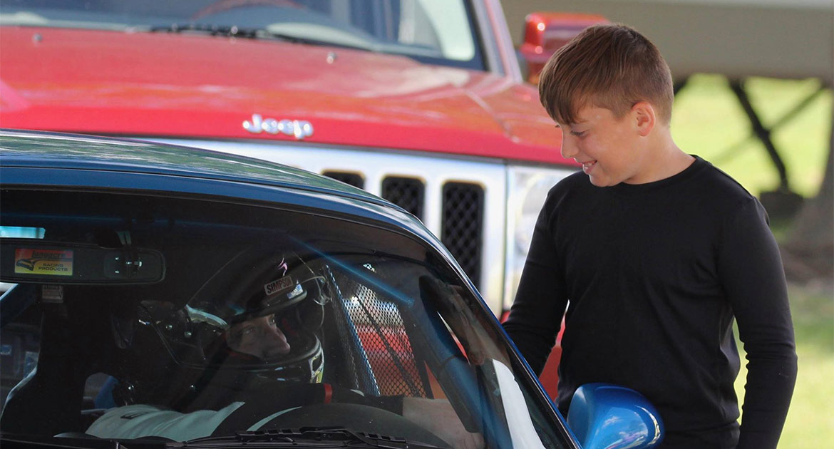 Boy talking to man in a race car before taking off down the track