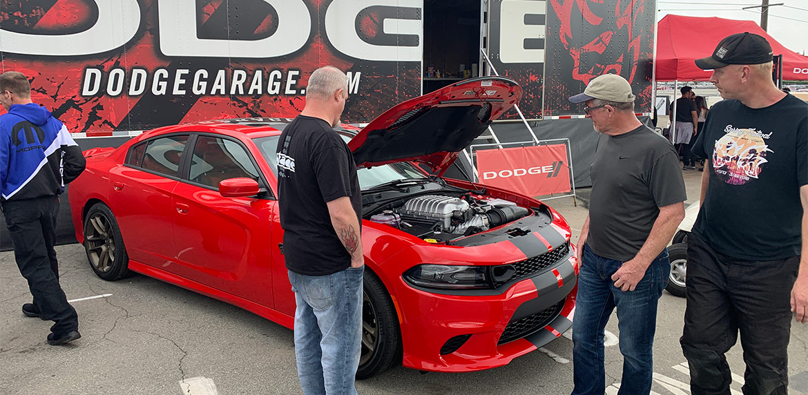 Attendees of Spring Fest looking at the engine of a red Charger