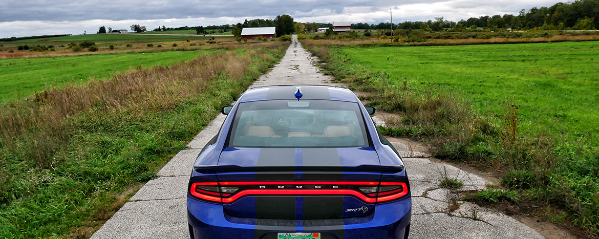 Blue Charger Hellcat driving down a deserted road