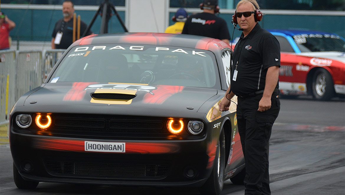 Kevin Helms standing beside Leah's Challenger Drag Pak waiting to race