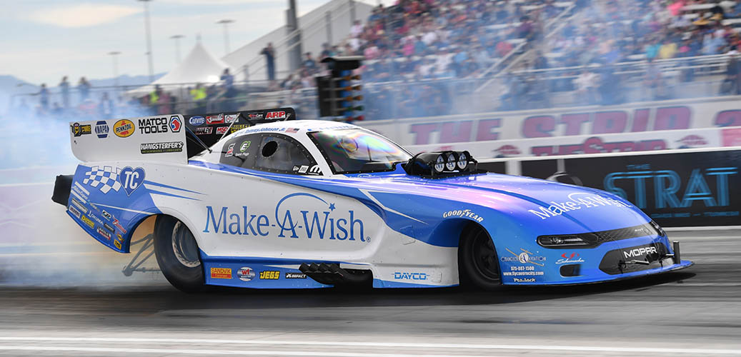 Tommy Johnson Jr. Racing his Dodge Charger SRT Hellcat Funny Car down the track with a crowd of fans in the background