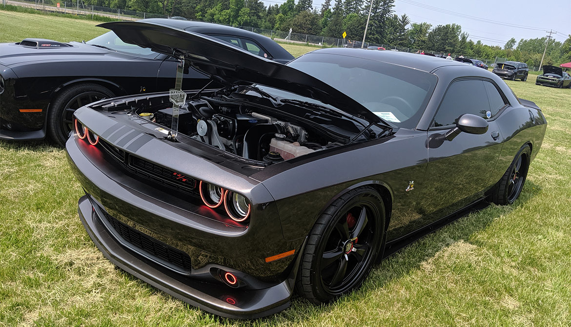 Black Dodge Challenger Scat Pack with the hood up on display at Mopars at the Park