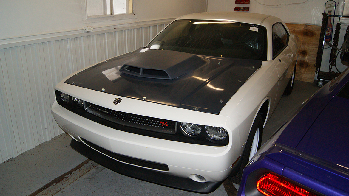 a white and black dodge challenger parked in a garage