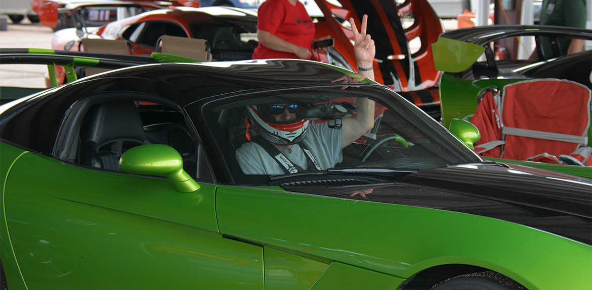 a man sitting in a dodge viper and giving the peace sign out the window