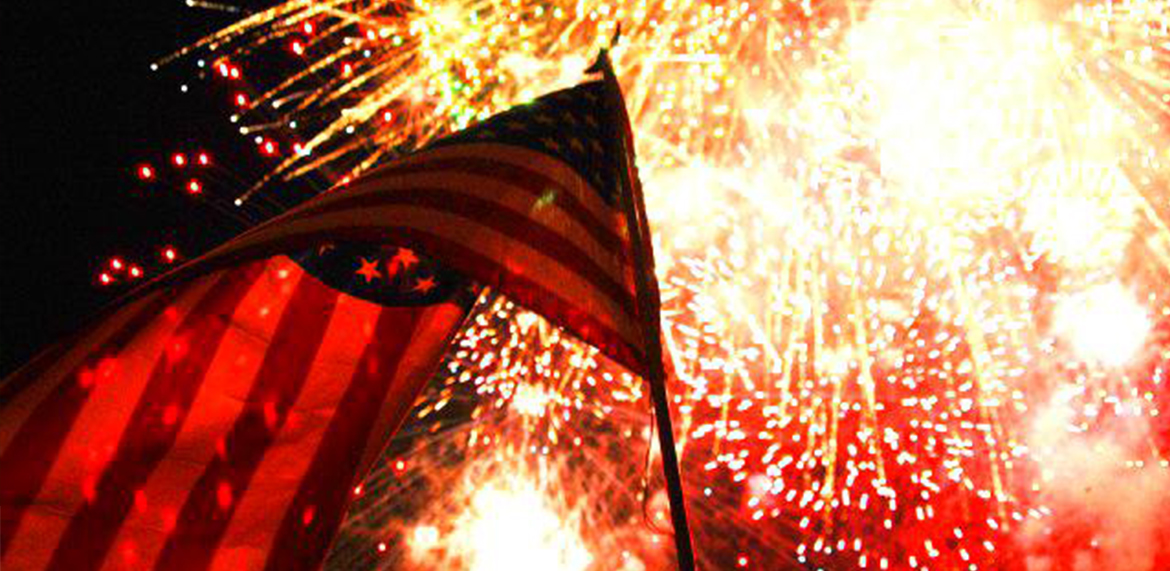 an american flag with fireworks behind it 