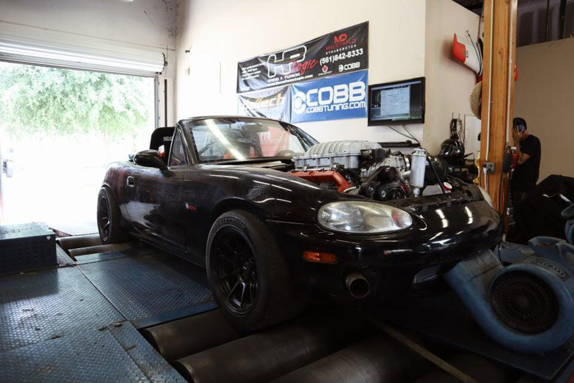 a black car in a garage with the hood taken off