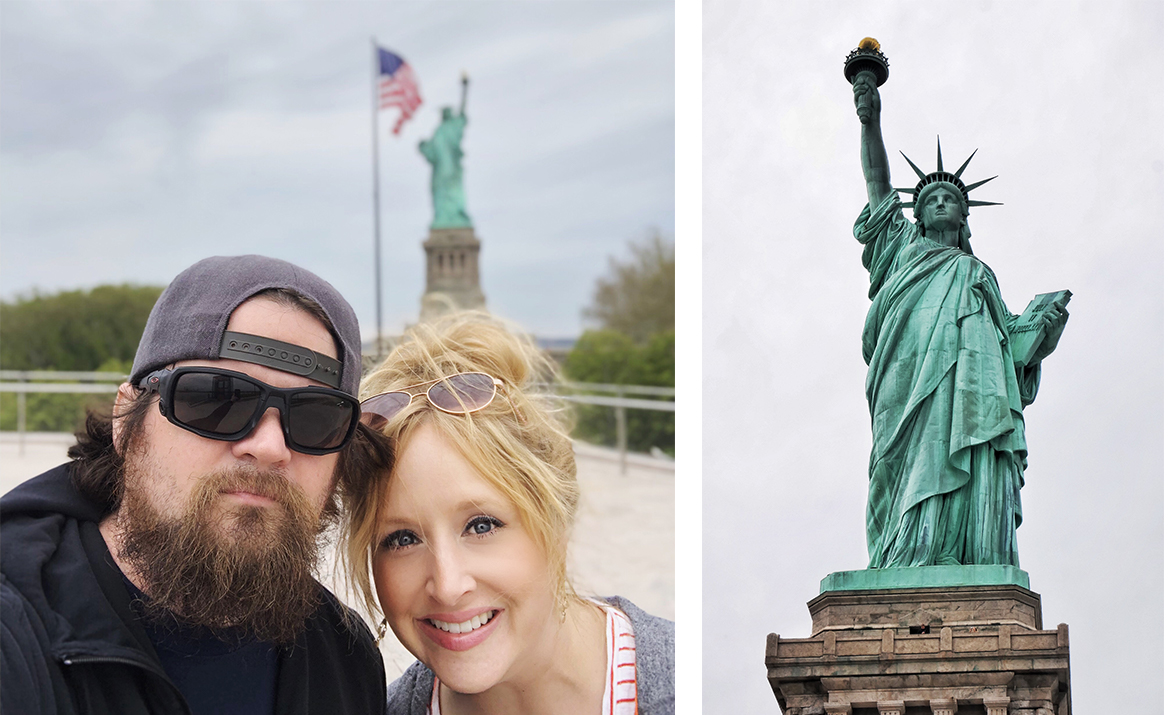 a man and woman posing in front of the statue of liberty