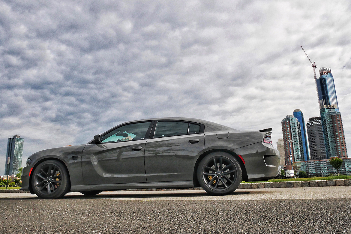 a gray dodge charger with skyscrapers behind it