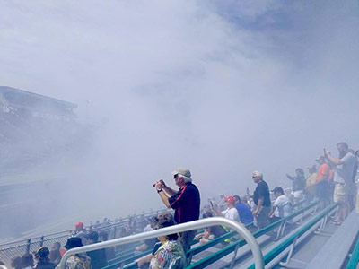 fans in a bleachers watching a car do a burnout