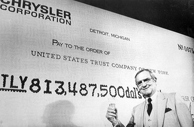 lee iacocca standing in front of a picture of a check 