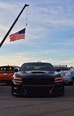 dodge vehicles parked outside with an american flag hanging over them