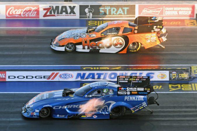 two funny cars on the starting line of a drag strip