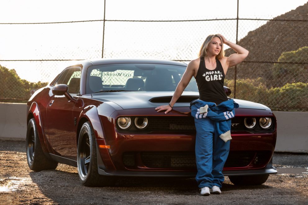 woman wearing a mechanic suit with a dodge challenger