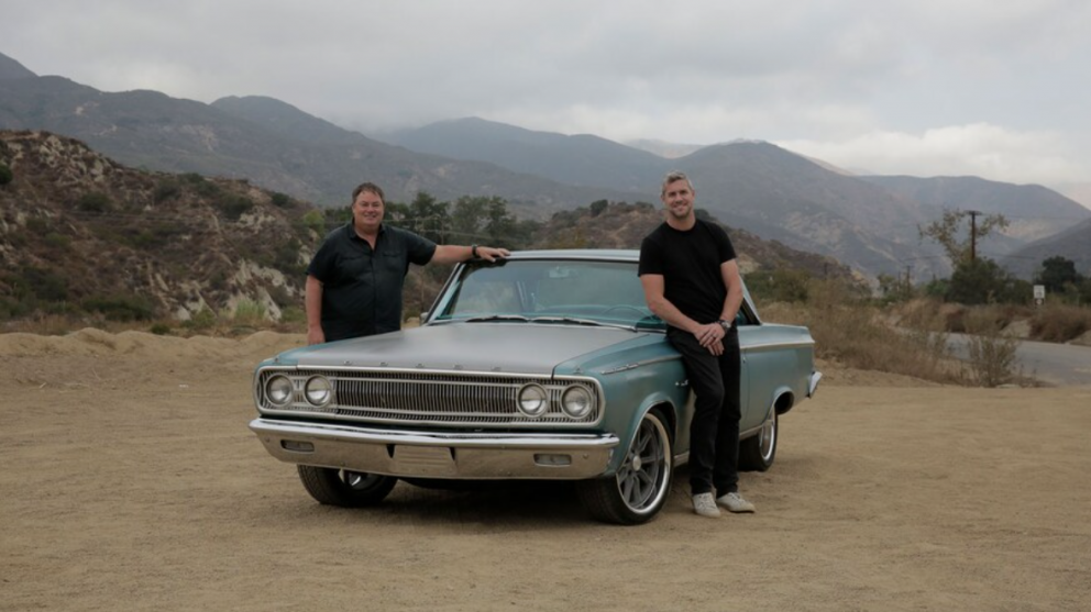 2 men standing beside their 1965 Dodge Coronet
