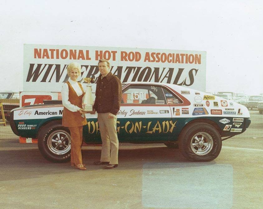 Shirley and H.L. holding a trophy in front of her drag car