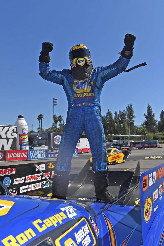 Ron Capps standing on his car in celebration after a win