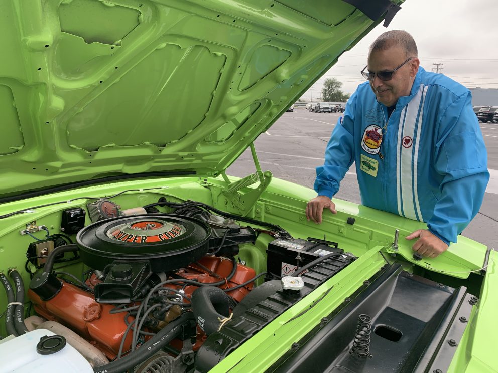 Man looking at the engine of a Plymouth Road Runner
