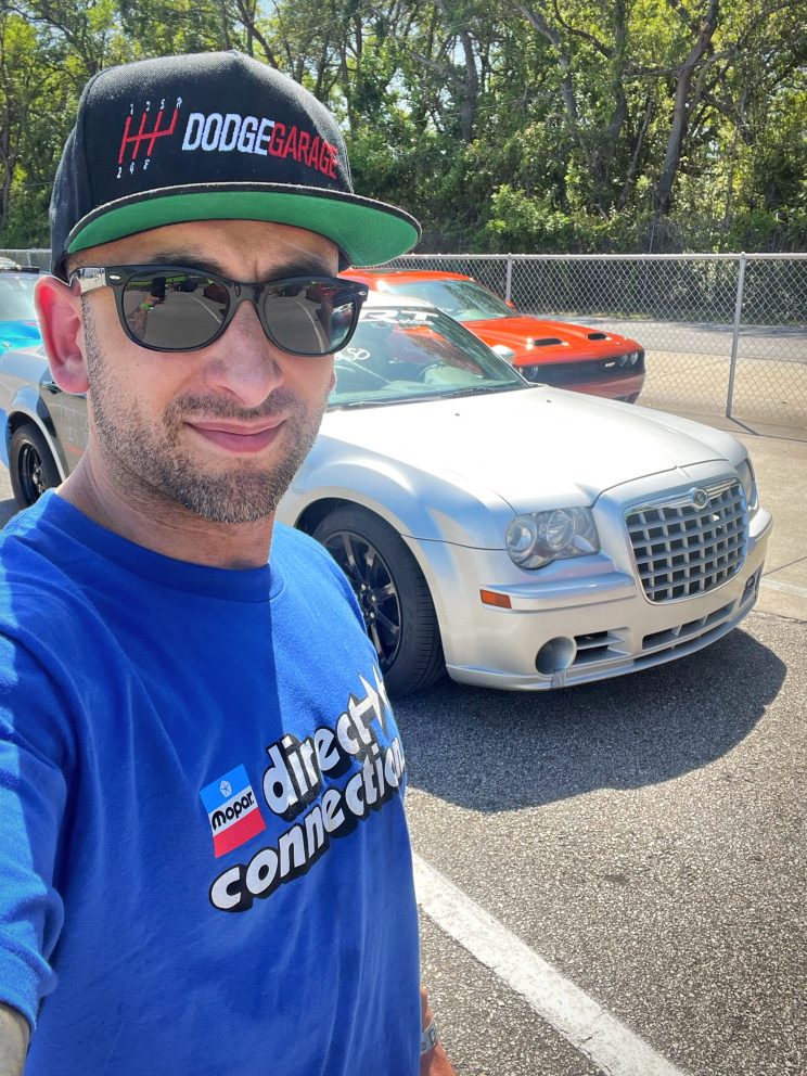 man posing with his car