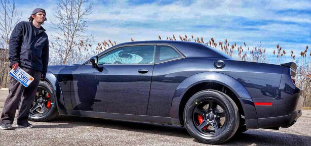 Man holding a licesnse plate next to a Dodge SRT Demon