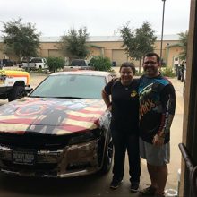 Two people posed next to a Dodge Charger