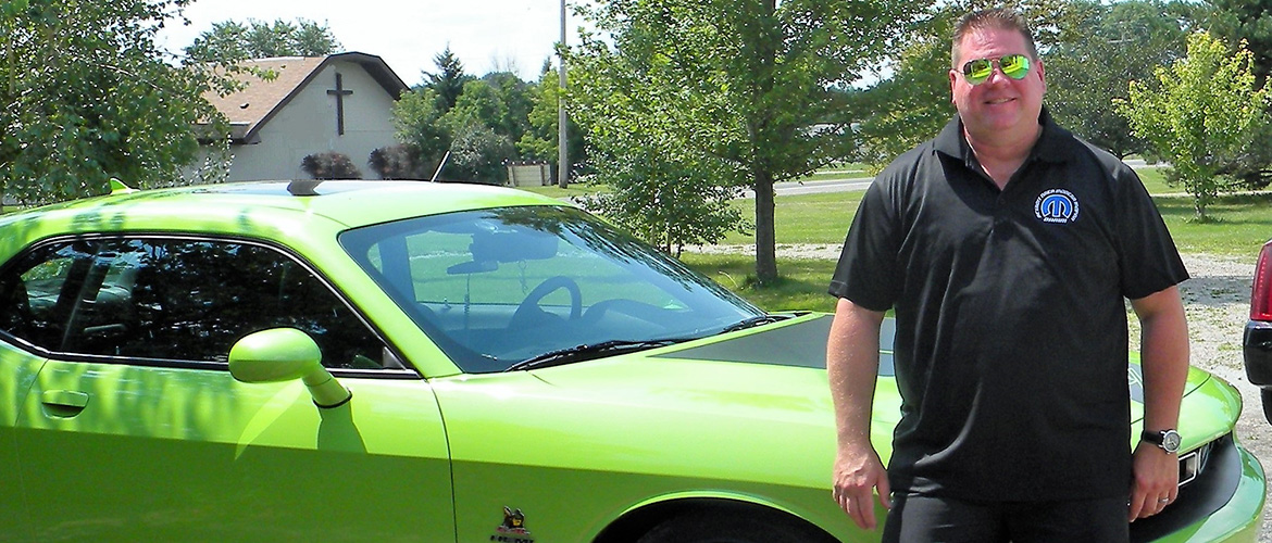 man standing infront of his Dodge Green scat pack challenger