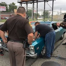 Police officers examining an older blue challenger