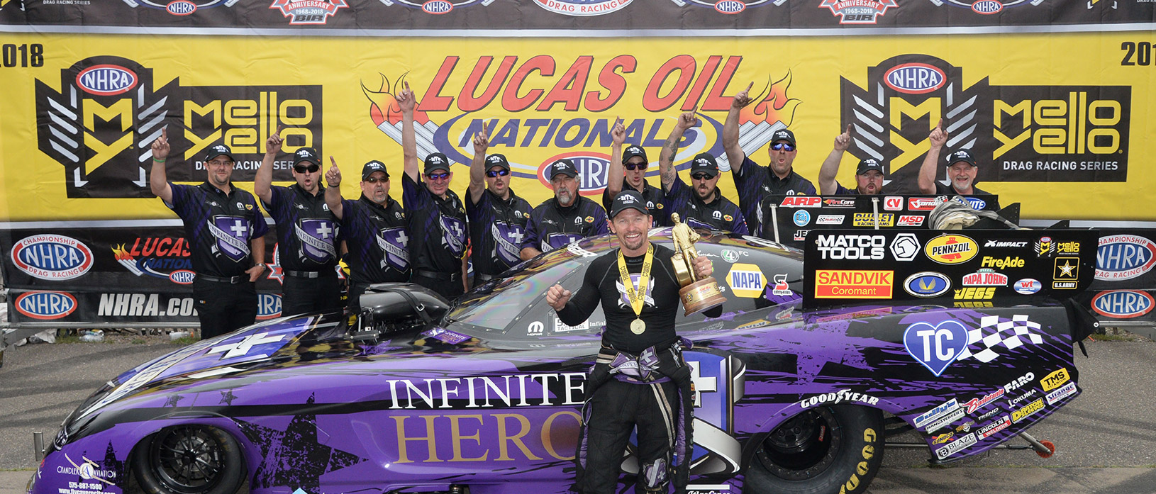 Man posing with racecar and team after wining Lucas oil nationals