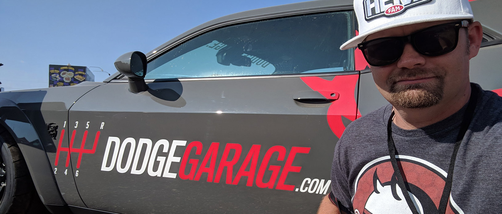 man taking a selfie with Dodge Garage promo challenger
