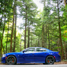 Blue 2018 Dodge Charger SRT Hellcat parked alongside road with towering trees in the back ground