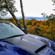 Blue 2018 Dodge Charger SRT Hellcat driving along road with trees changing color