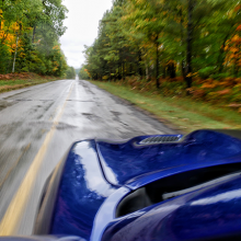 Blue 2018 Dodge Charger SRT Hellcat driving along road with trees changing color