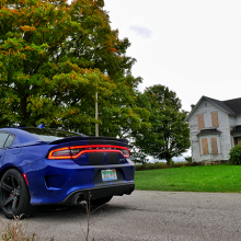 Blue 2018 Dodge Charger SRT Hellcat parked in front of abandoned farm house