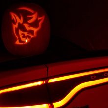 Dodge Demon pumpkin sitting on the trunk of a Dodge Charger
