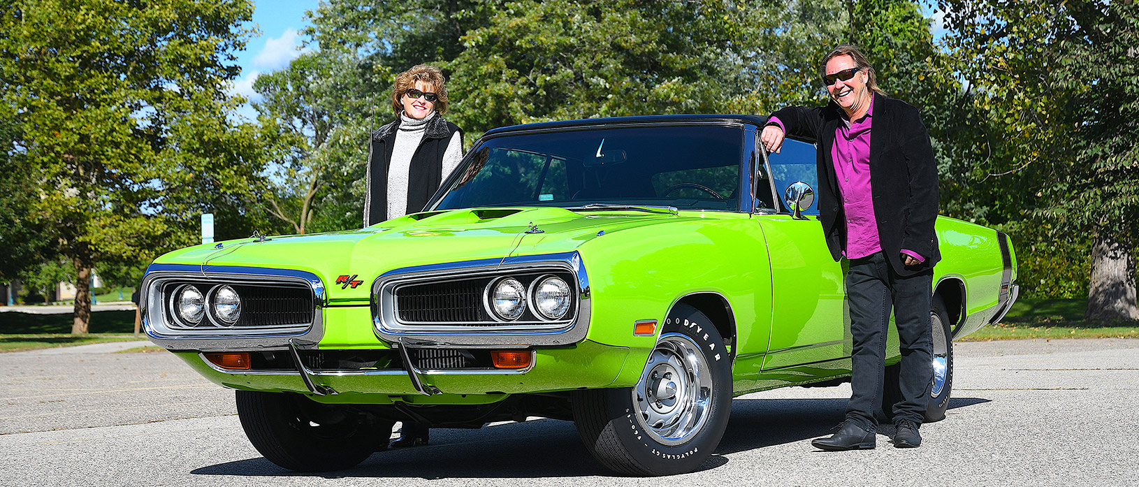 Mark Young and his wife standing beside their green 1070 Coronet R/T convertible