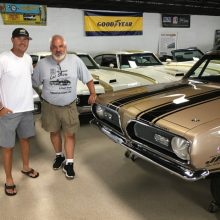 Two men standing next to a 1969 Hurst HEMI Under Glass