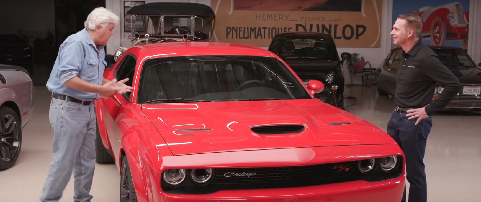 Jay Leno talking to Steve Beahm around a red Dodge Challenger