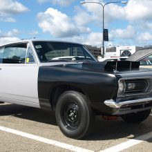 This Plymouth BO29 HEMI Barracuda is correctly presented in gray primer and black gel-coat. As with the LO23 HEMI Darts, body color was applied by the buyer after retail delivery. Chrysler did this to force teams to (hopefully) apply highly visible paint jobs and graphics, all the better to catch the eye of spectators (and magazine photographers) on race day. Dodge did not want HEMI Darts roaming the street. The stark black steel wheels and bare hubs are correct.