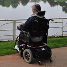 GL Woods sitting in a wheelchair in front of a lake