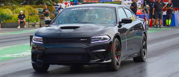 Black Dodge Charger SRT racing down the drag strip at NMCA