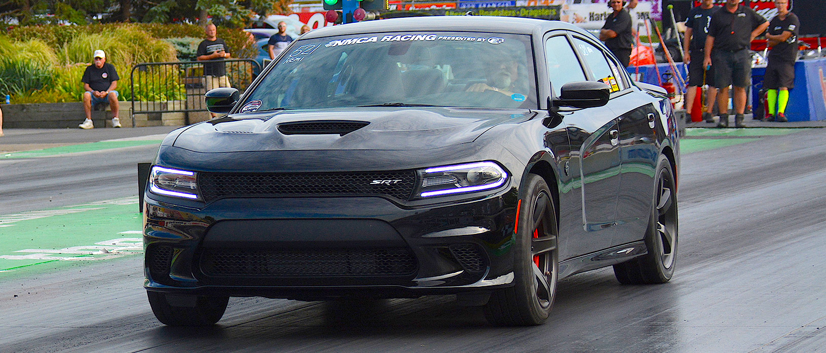 Black Dodge Charger SRT racing down the drag strip at NMCA