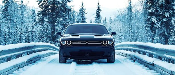 Dodge Challenger driving across a bridge in the snow