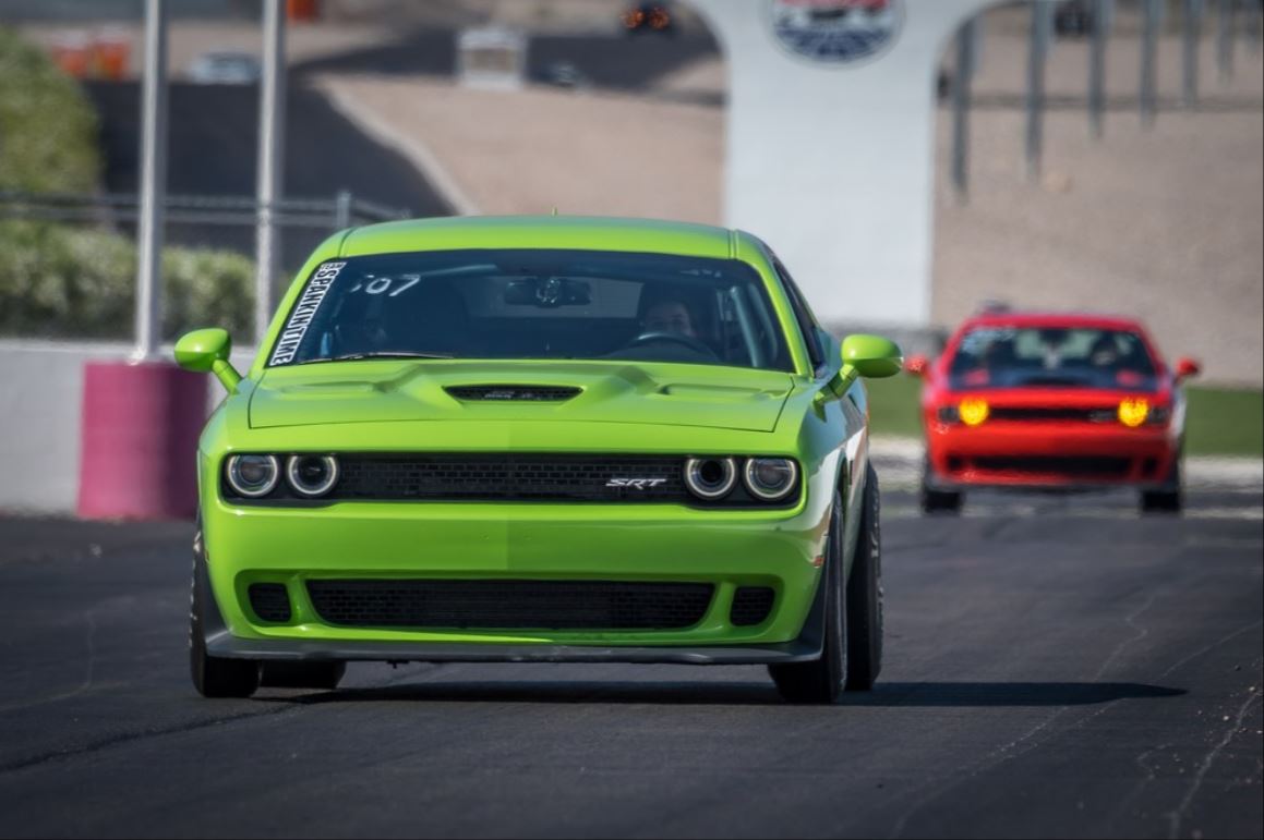 Green Dodge Challenger SRT Hellcat racing down the drag strip