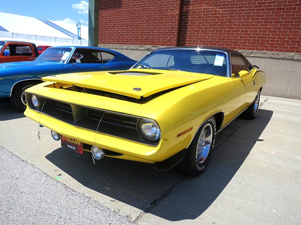 Yellow older challenger convertable with hood popped.