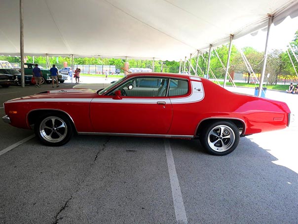 Red challenger with white stripe parked under a tent.