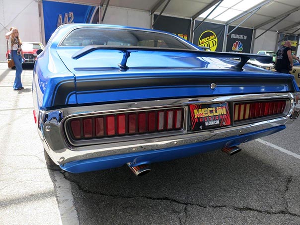 Rear view of a blue challenger with license plate that reads 'mecum'.