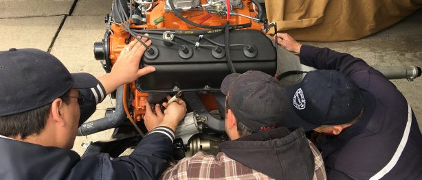 Michael, Erik, and Dave Belcarz work on an engine together.