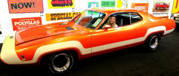 A young lady in an orange and white older vehicle at Steven Juliano's private collection.