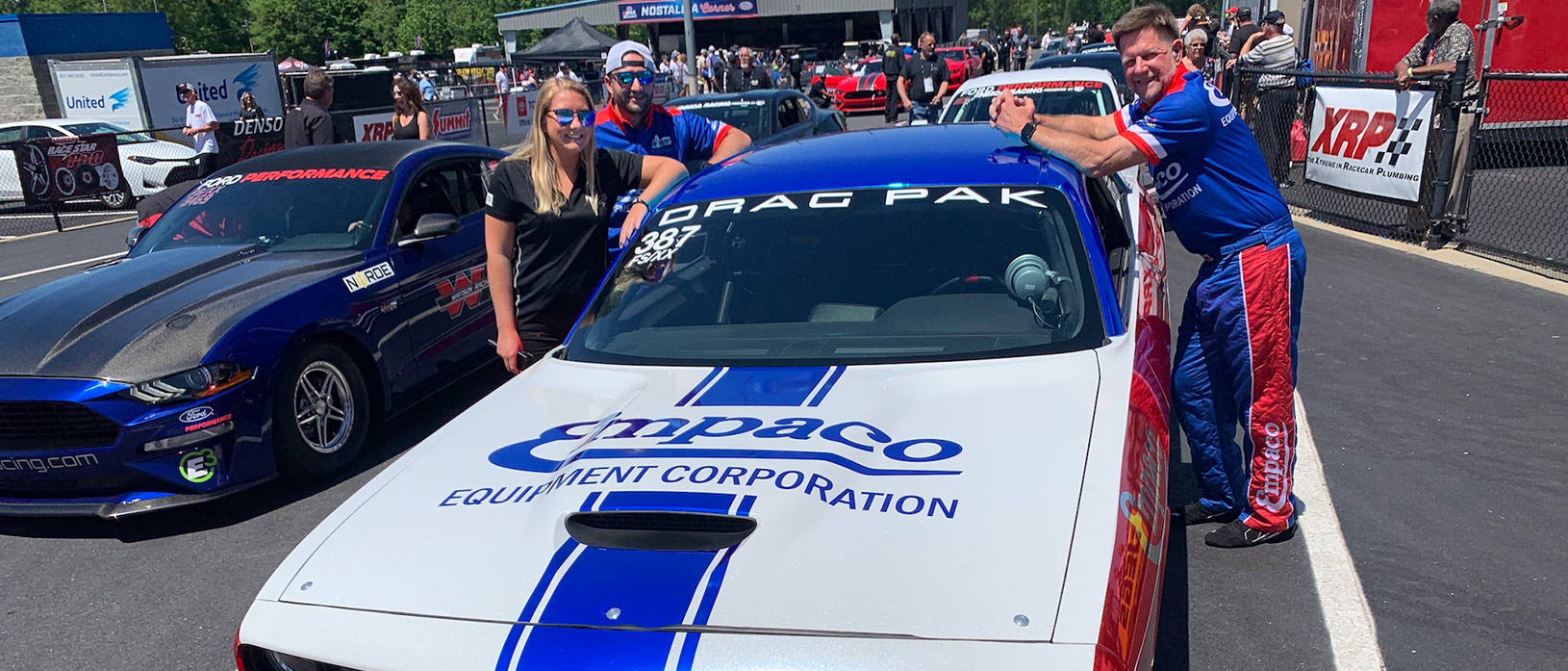 Crew leaning against a Empaco Equipment Corporation Drag Pack Challenger at a race